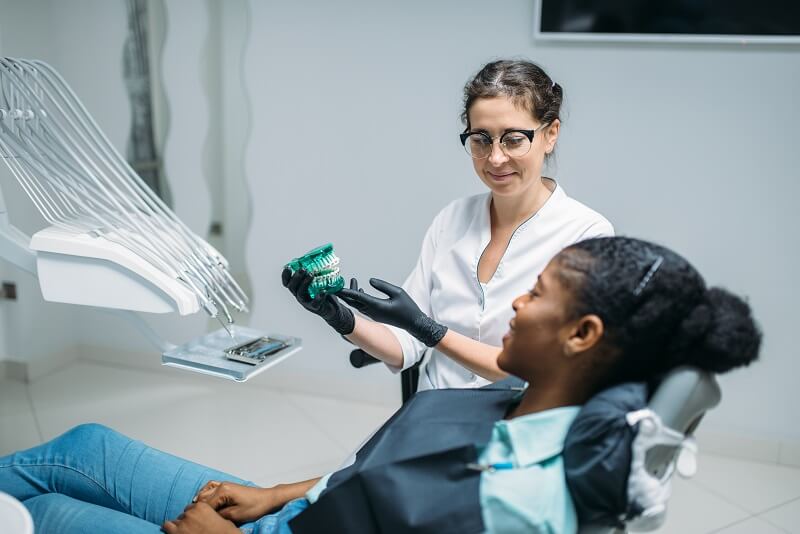 dentist shows dentures to woman in a dental chair 4ERHV5T