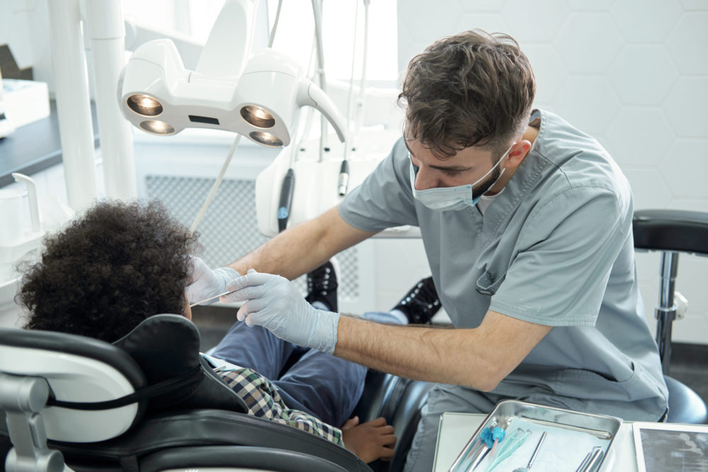 dentist bending over little boy while drilling his 2022 01 20 15 49 24 utc scaled e1685520796997