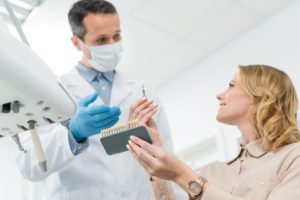 首頁 13 doctor showing tooth implants to female patient in 2022 12 16 17 54 11 utc